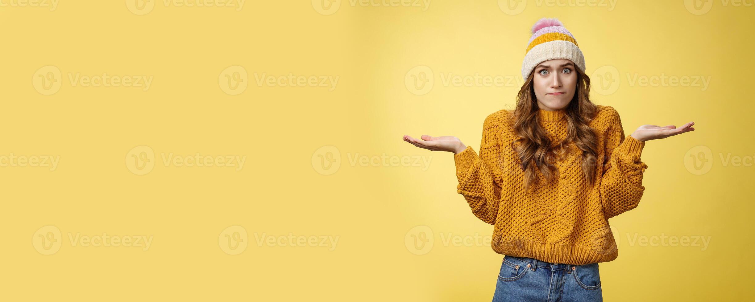How should I know. Portrait confused perplexed worried cute female assistant shrugging spread hands sideways clueless unaware cannot understand what happened unsure, unaware yellow background photo