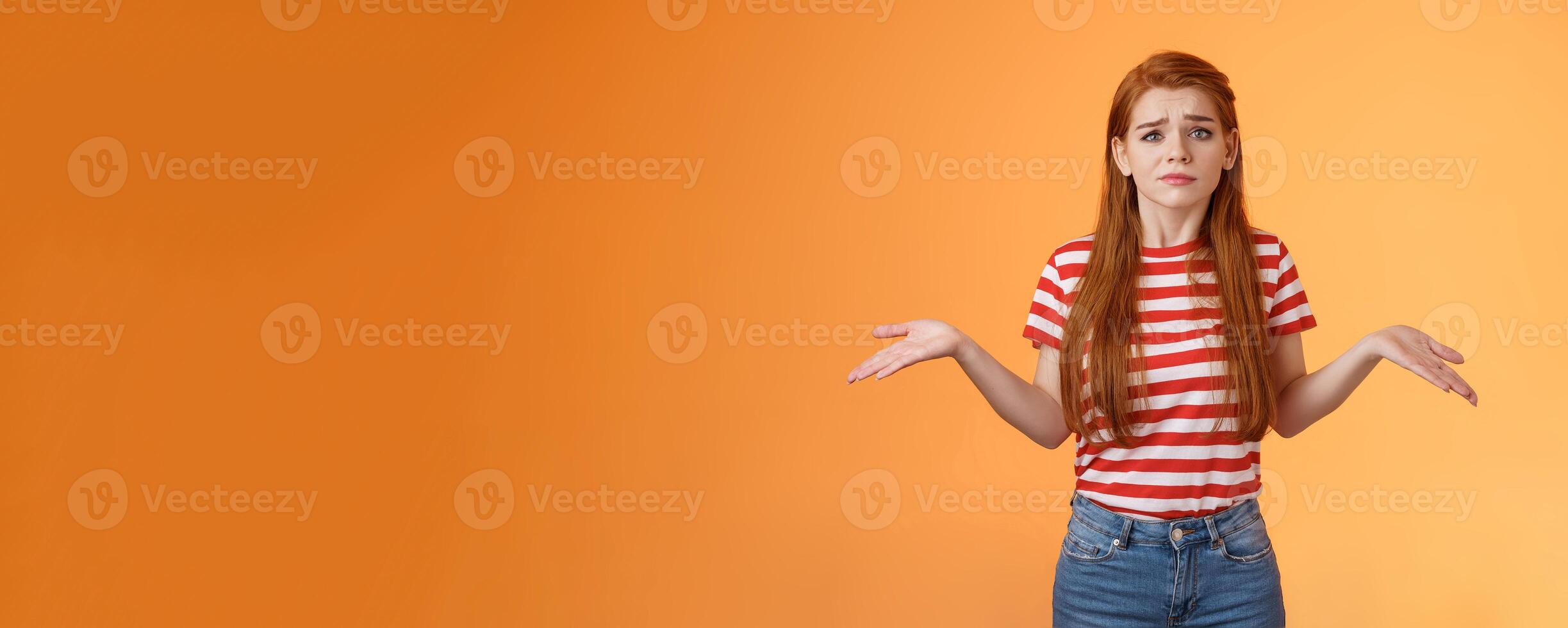 Uneasy questioned and clueless lovely modern stylish redhead woman shrugging spread hands sideways unaware, grimacing perplexed, tough question, have no answer, stand orange background photo