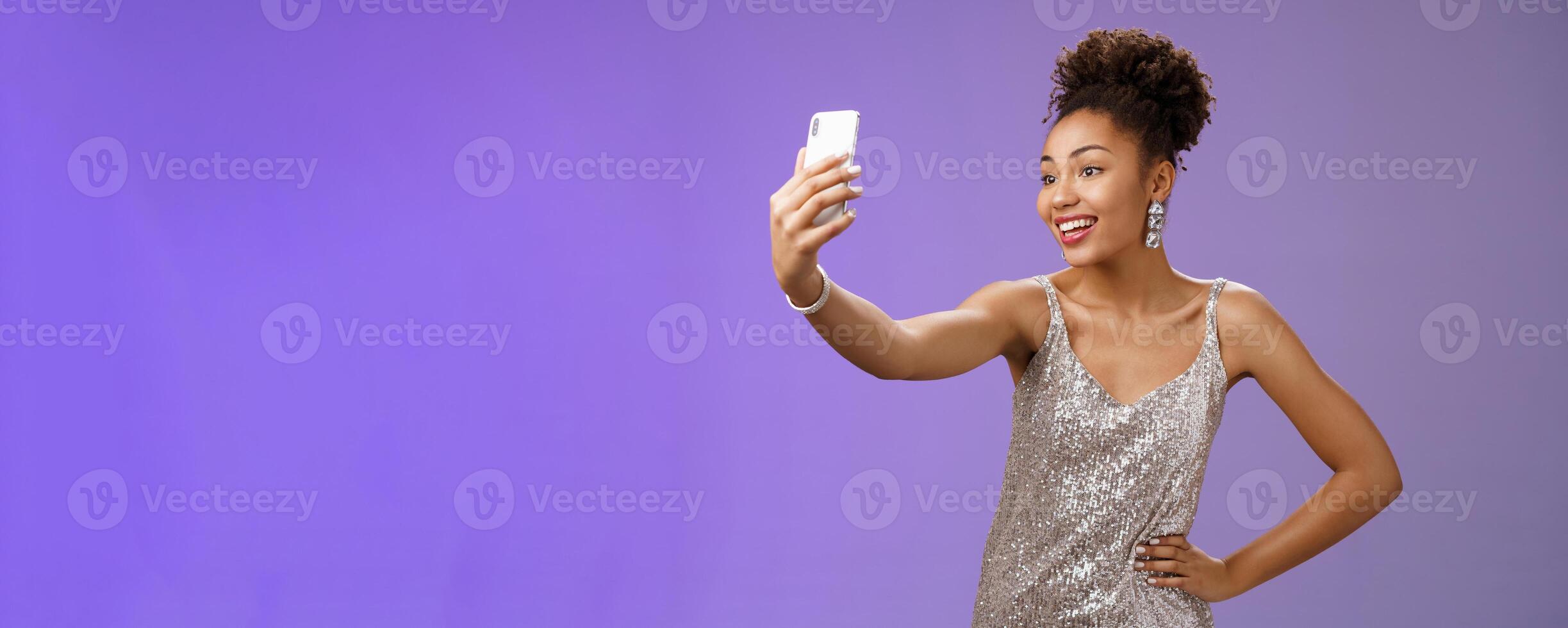 Confident glad attractive stylish millennial african-american woman in silver glittering dress taking selfie posing cute sassy hold hand waist extend arm record message during night-out photo