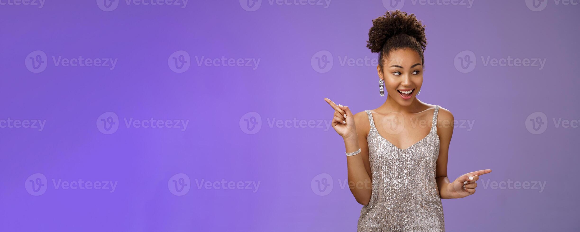 Good-looking excited glamour african-american female student attend luxurious event in silver shiny perfect dress dancing look around pointing right left smiling pleased variants make choice photo