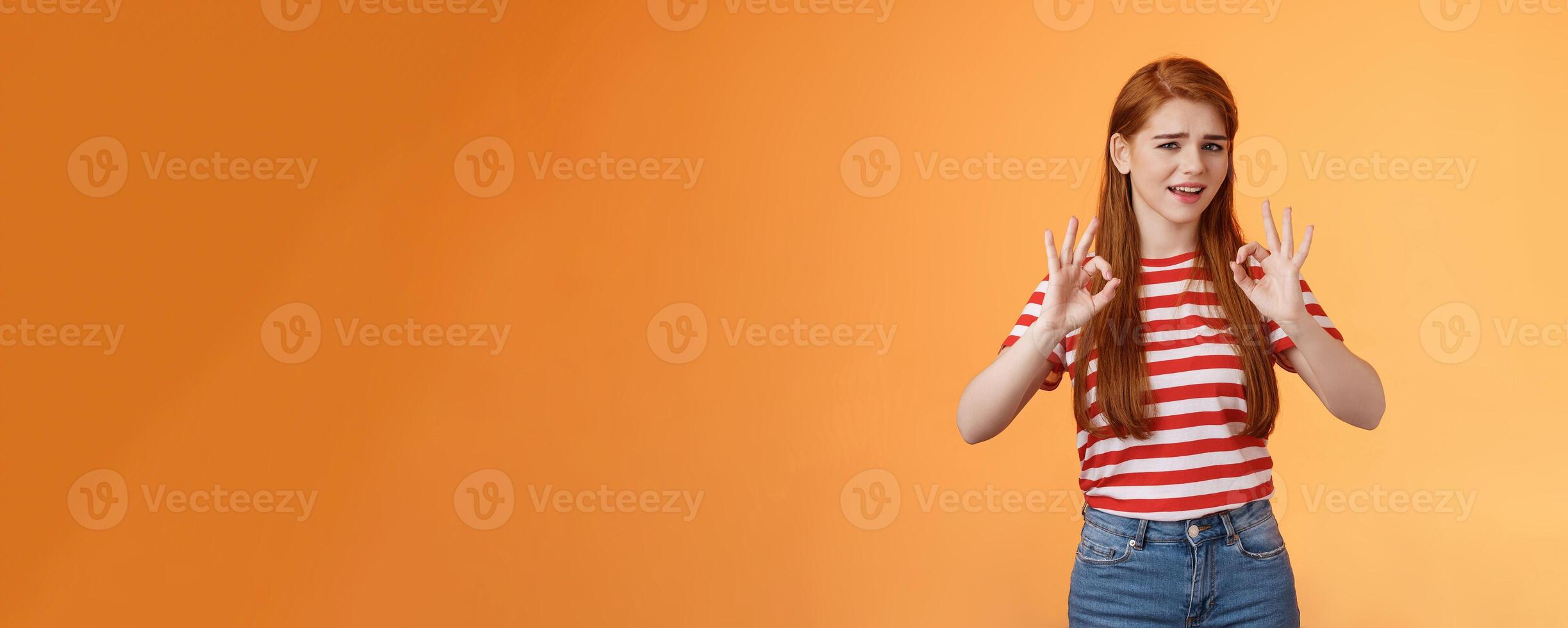 Chill carefree relaxed redhead girl assure everything fine, make okay signs, approval, nothing worry about everything good, stand orange background unbothered, satisfied not bad result photo