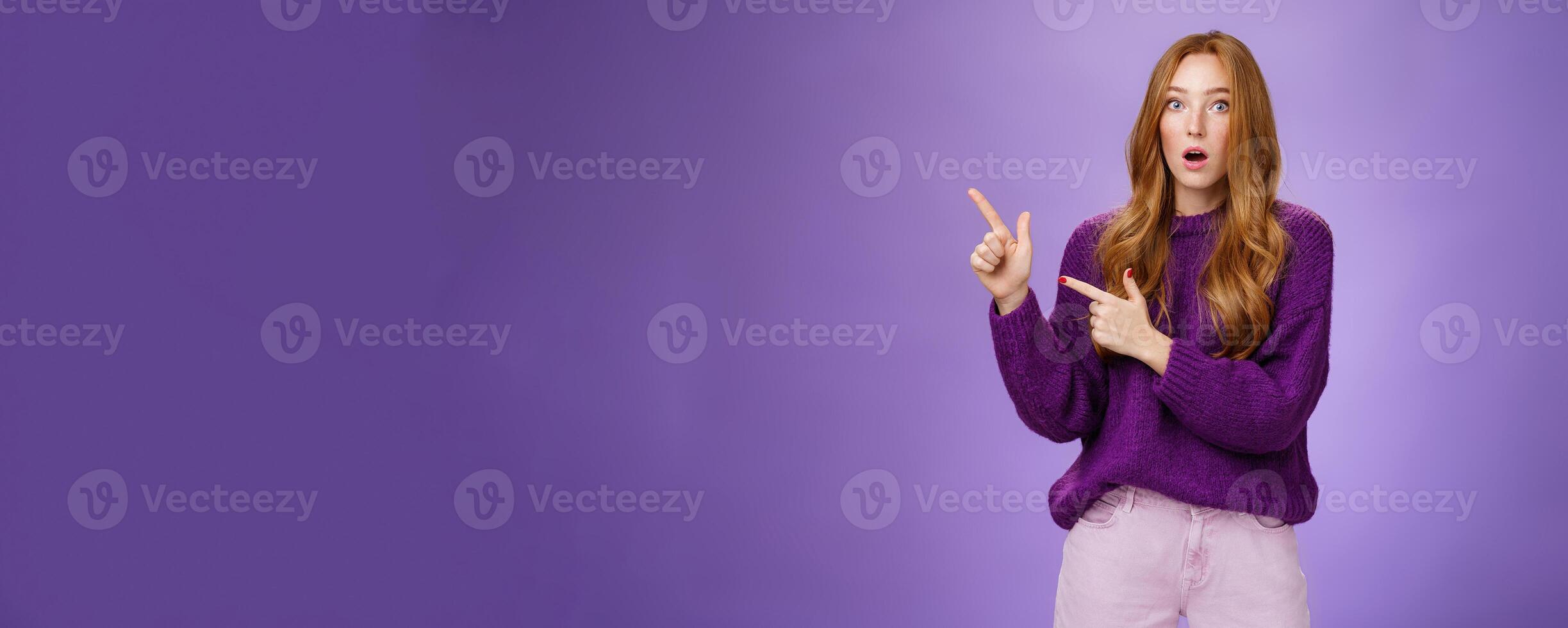 Stunned girl asking friend if she saw it drop jaw from stupor and amazement popping eyes at camera after witnessing shocking revelation pointing questioned at upper left corner over purple wall photo