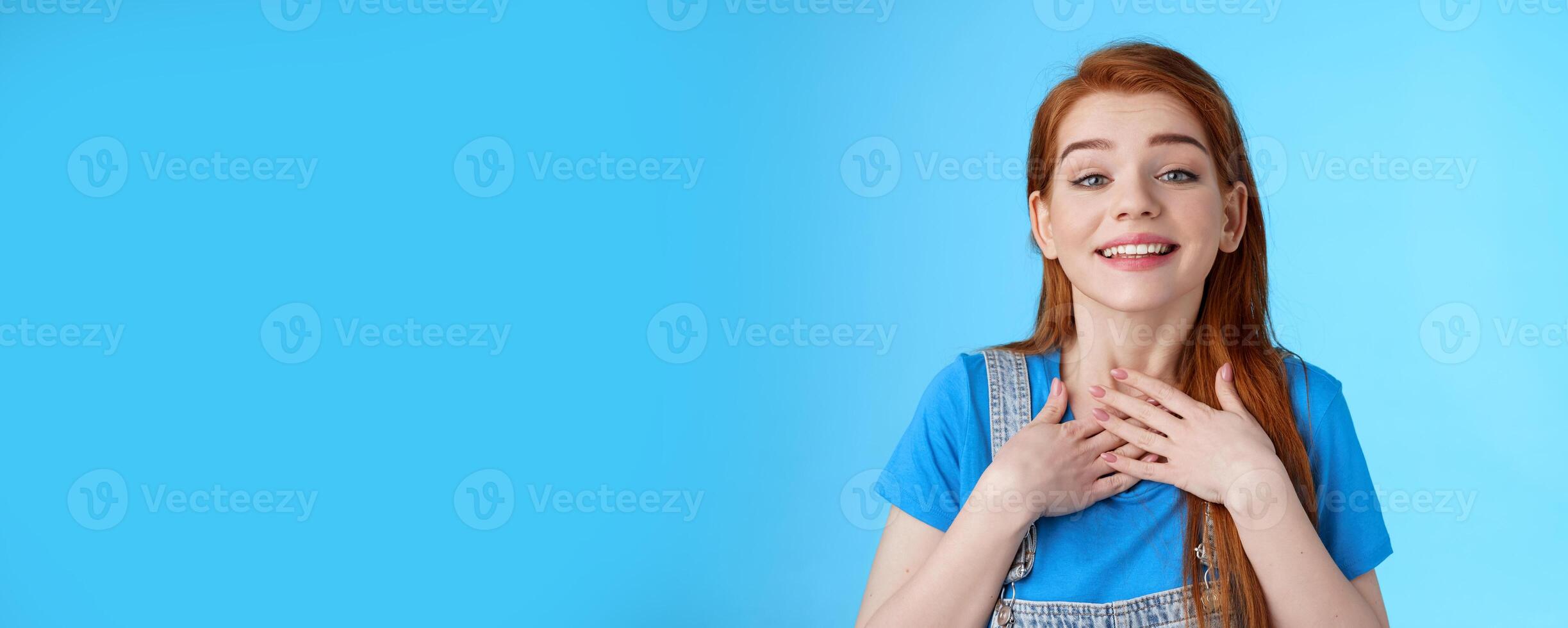 Grateful sincere cute charming redhead female thanking friends, smiling delighted appreciate nice tender gesture, press palms chest heart, grateful, look admiration and love, stand blue background photo