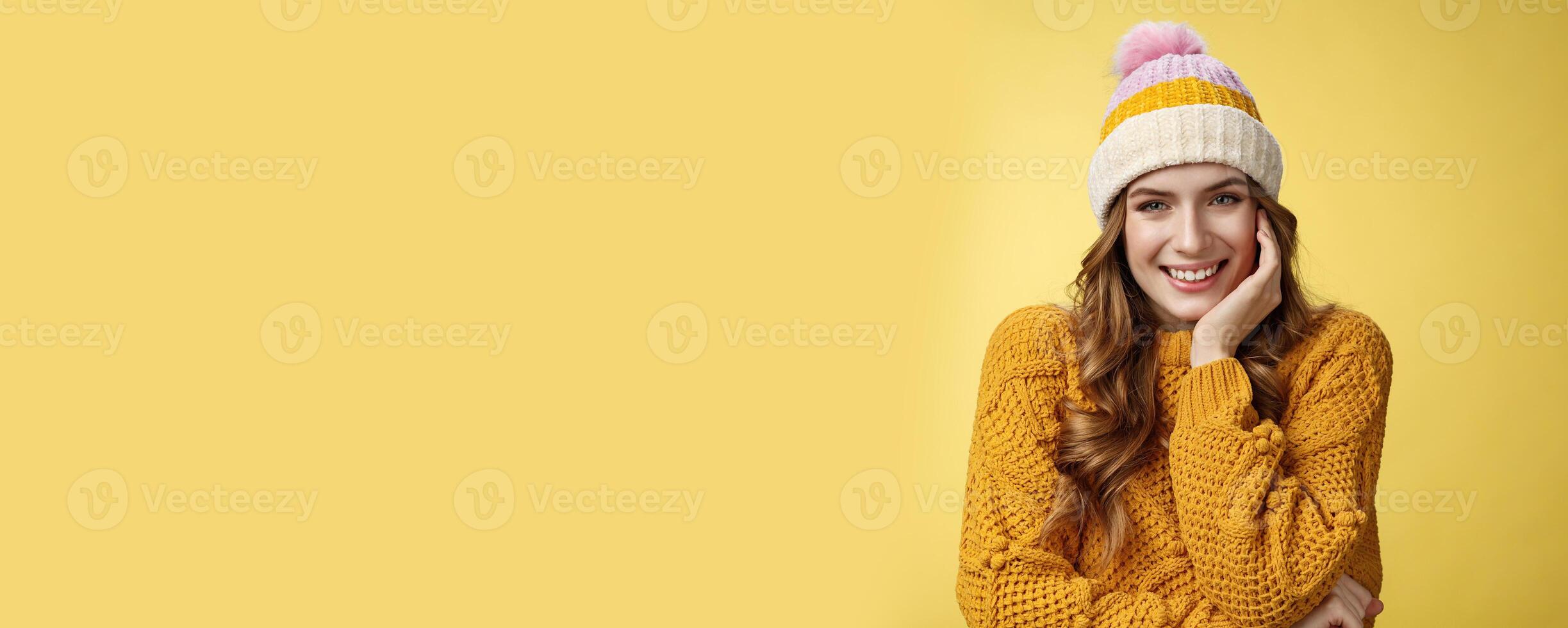 Dreamy tender romantic good-looking woman wearing warm hat knitted sweater giggling smiling flirty seducing you look interested happy, lean head palm listening curious story, yellow background photo
