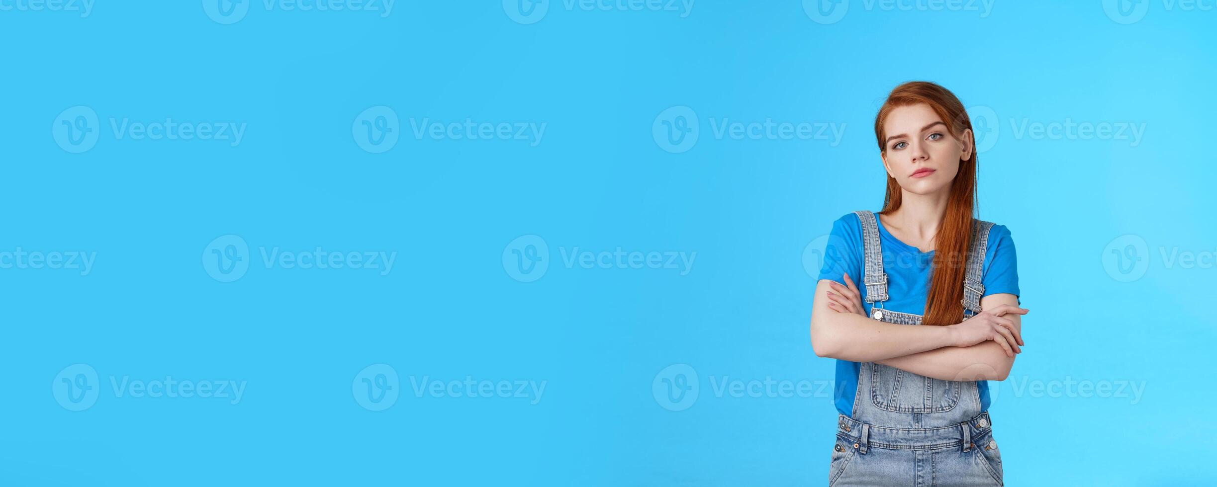 Serious-looking professional bossy redhead female skilfull girl, cross arms confident self-assured pose, look camera no emotions strict determined, aim win, stand blue background encouraged photo