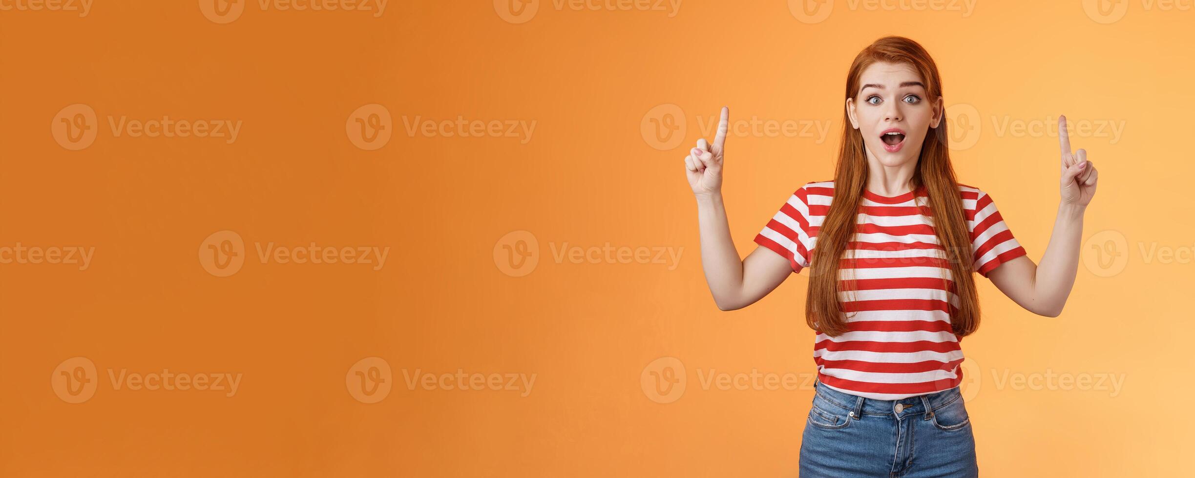 Surprised cute girl 20s long red hair lovely ears, inspired awesome interesting lecture showing you copy space up promo, open mouth amused, fascinated stare camera, explain news photo