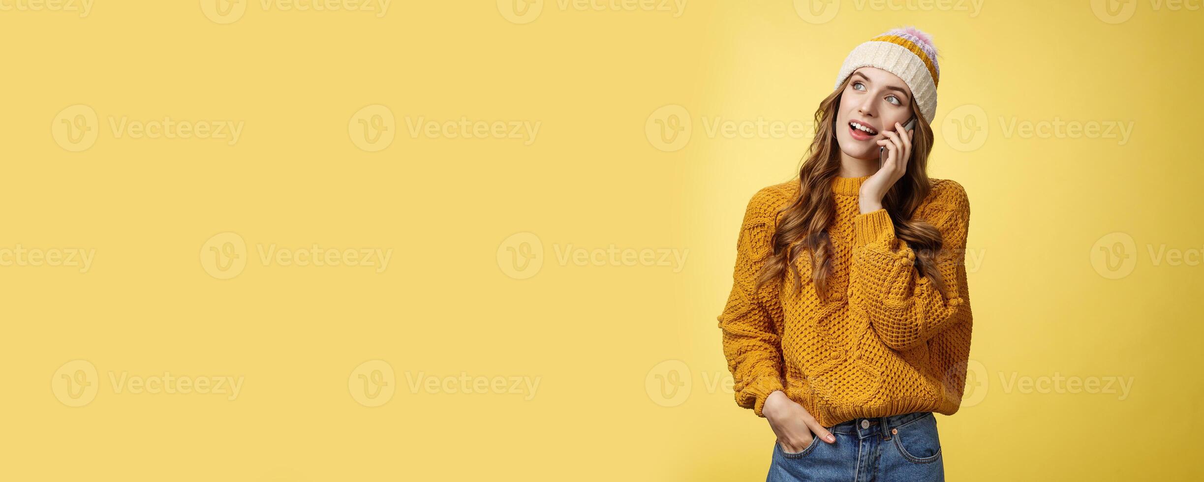 Attractive young female office trainee ordering food calling restaurant via smartphone making appointment wondering when friend free have mobile phone conversation looking away casually photo