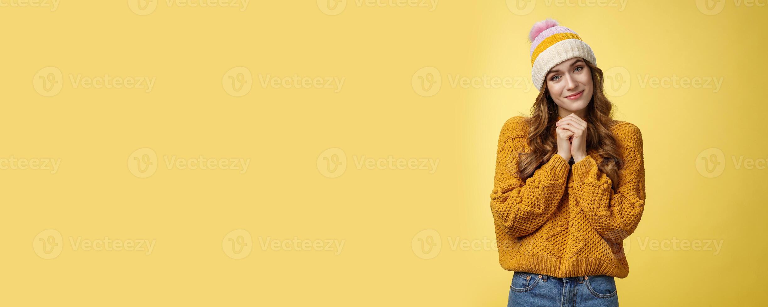 Touched charming cute silly young girl make flirty gazes camera press palms together checking out something moving cute, tilting head seeing adorable kitten, smiling delighted yellow background photo