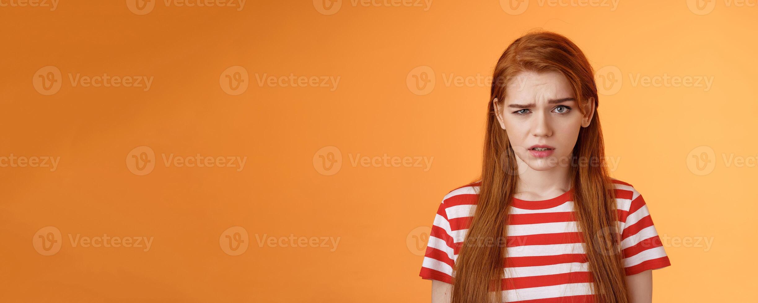 Close-up stupified puzzled redhead perplexed woman, open mouth raise eyebrow full disbelief, confused frowning, cannot understand person saying nonsense, stand questioned orange background photo