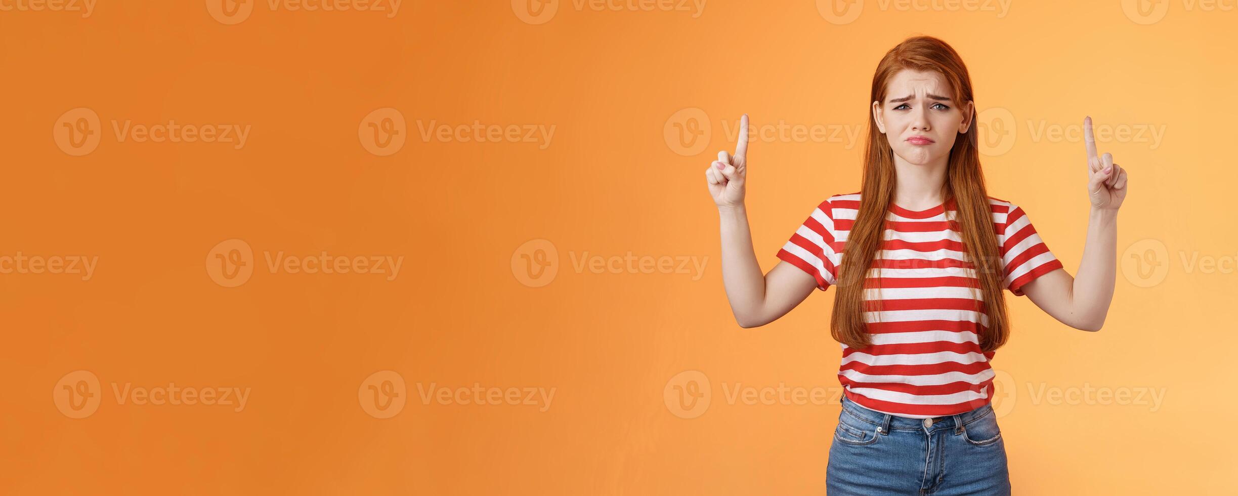 Disappointed upset cute whining timid redhead girl, gloomy face, pulling sad expression, complain, crying feeling regret loss, losing lottery, pointing up displeased, show despair and sorrow emotion photo