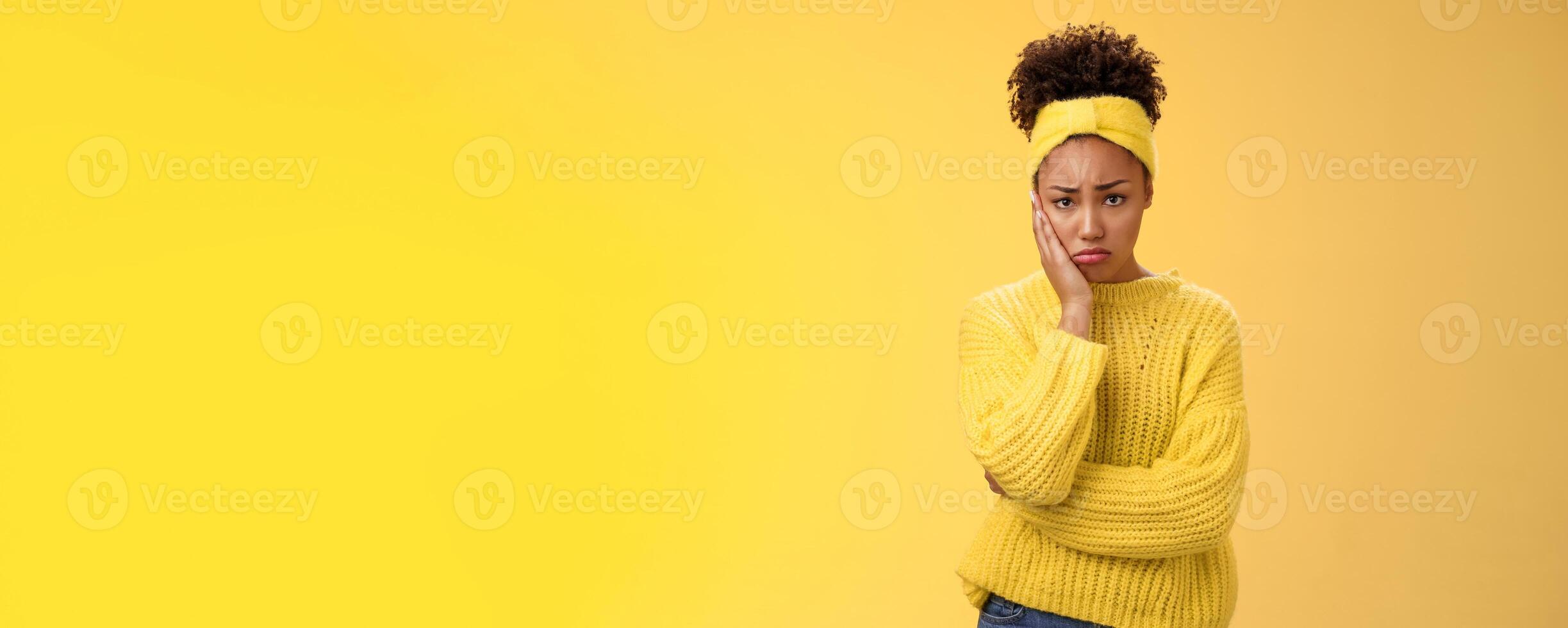 Upset cute gloomy young timid girl offended feel sadness regret touch cheek painful toothache make upset miserable pitty expression, troubled uncertain what do standing insecure yellow background photo