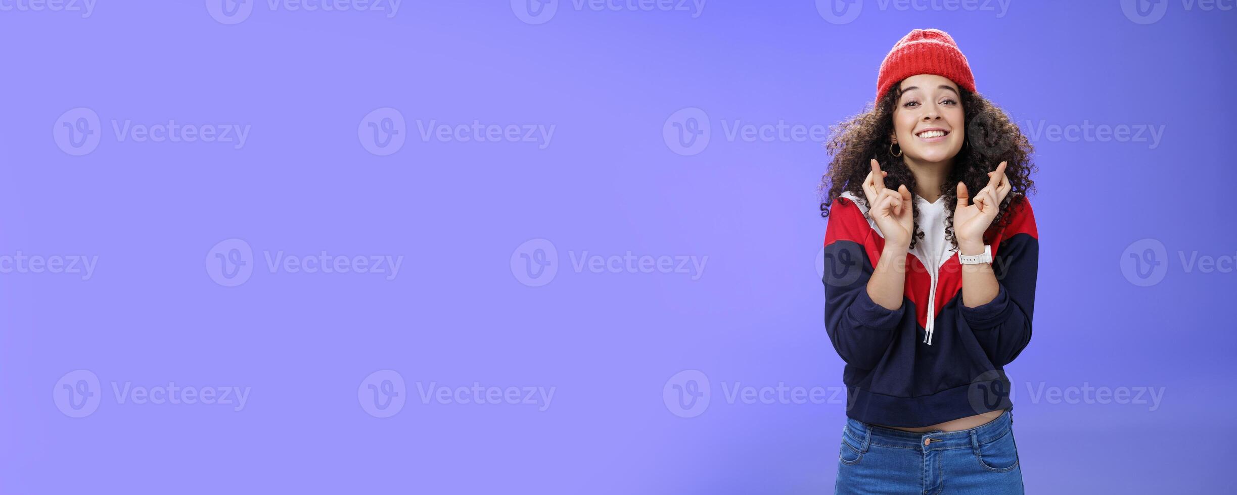 Dreamy optimistic woman praying friend will win standing supportive and excited smiling hopeful crossing fingers god good luck, waiting for miracle and dream come true posing against blue background photo