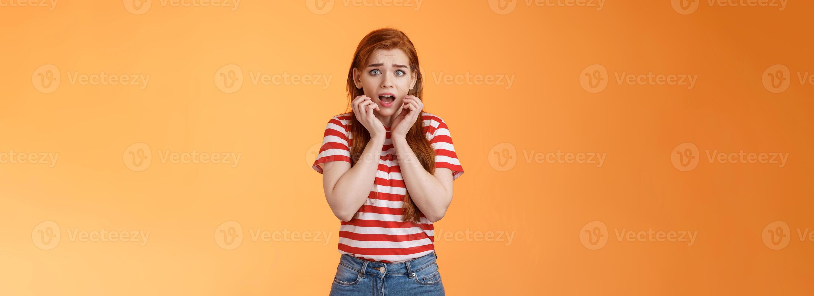 Innocent scared redhead female victim feel afraid standing stupor trembling fear, drop jaw gasping shocked, stare terrified, speechless look camera, frightened stand orange background photo