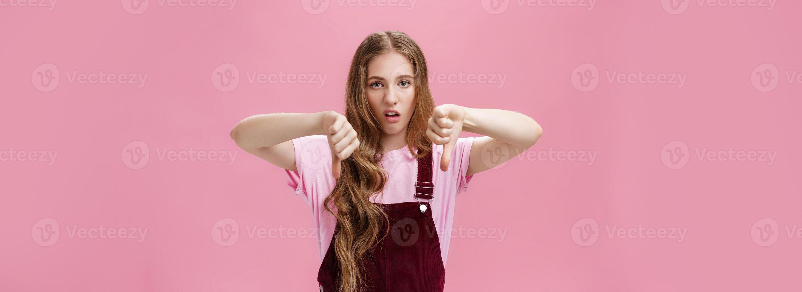 Body language, dislike and negative opinion concept. Portrait of displeased and unimpressed moody girlfriend being picky and arrogant showing thumbs down looking with disdain and disapproval photo