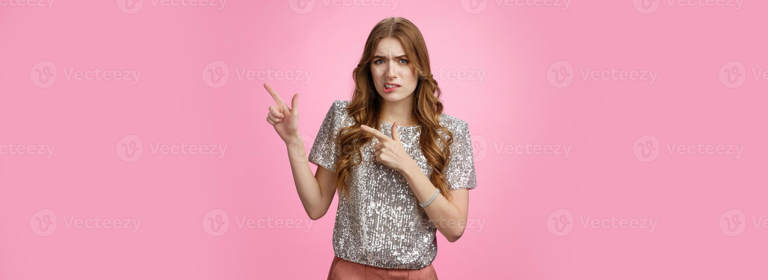 Unsure reluctant attractive glamour caucasian girl asking question doubtful pointing upper right corner lost seeking address party, grimacing cringe hesitant, standing uncertainpink background photo