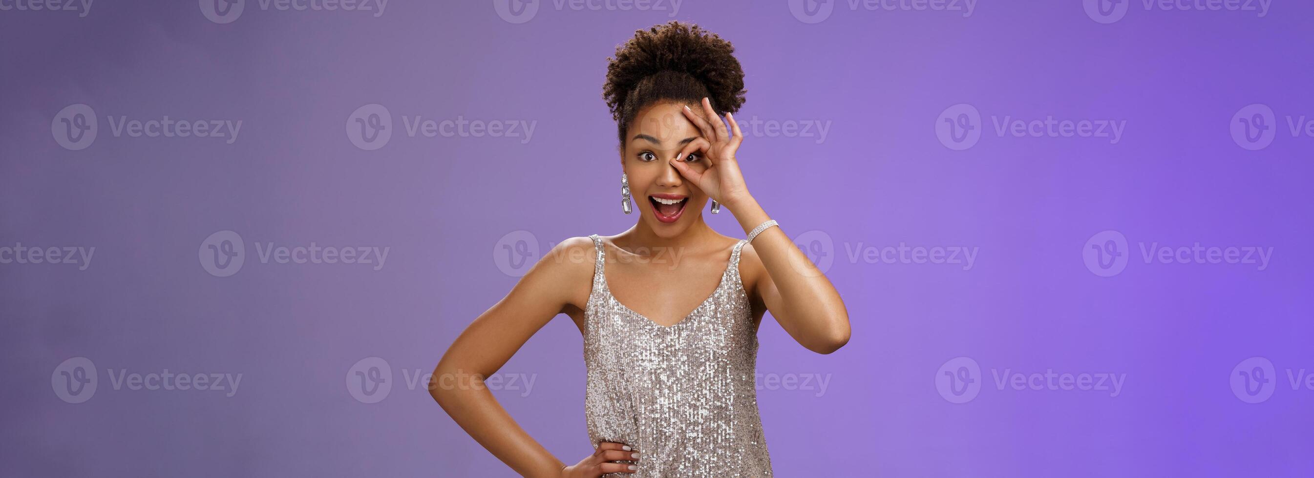 Good-looking charismatic enthusiastic flirty african-american woman in silver evening dress hold hand waist joyfully smiling open mouth impressed look through okay ok gesture amused photo