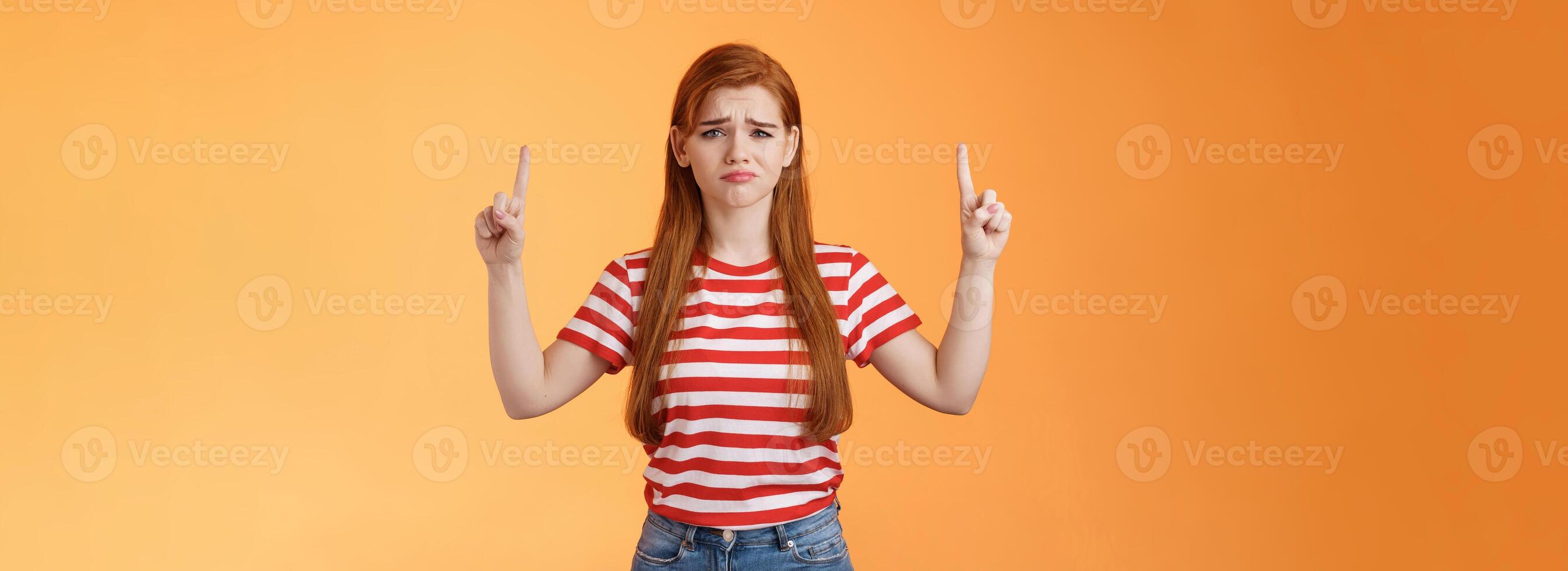 Disappointed upset cute whining timid redhead girl, gloomy face, pulling sad expression, complain, crying feeling regret loss, losing lottery, pointing up displeased, show despair and sorrow emotion photo