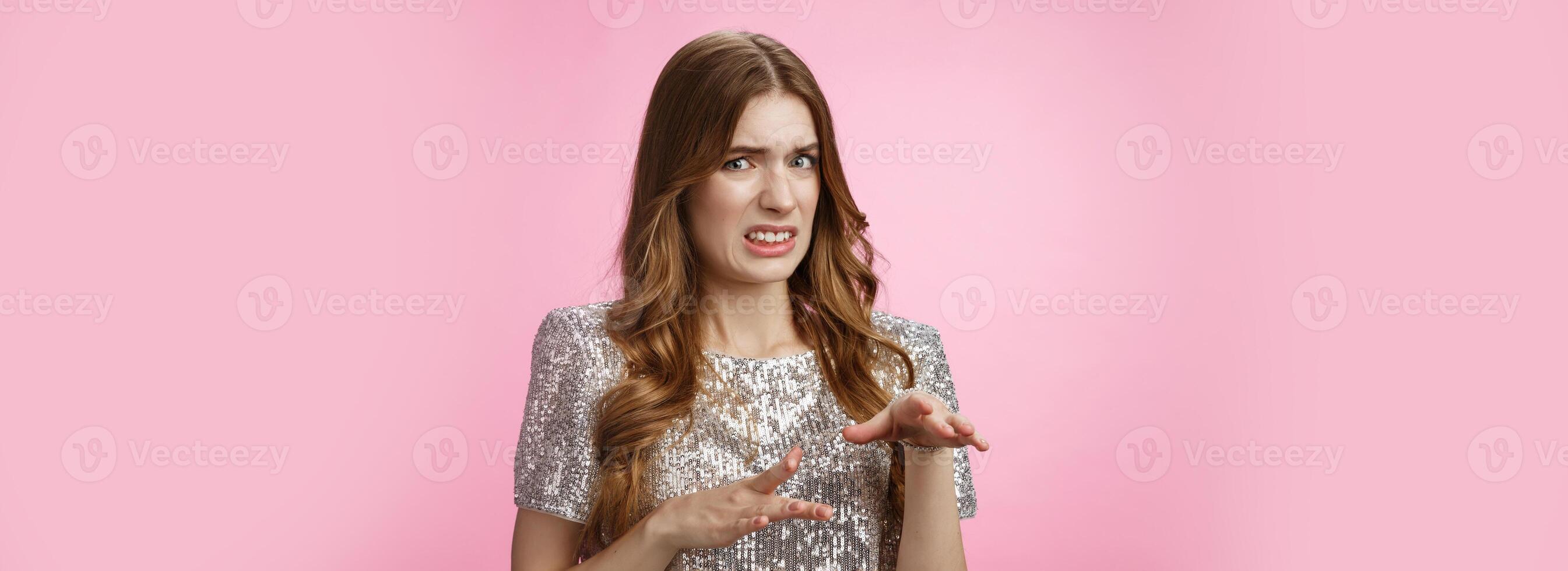 Disgusted reluctant young arrogant glamour woman telling about creepy man cringing aversion grimacing dislike gesturing displeased, expressing antipathy standing pink background freaked-out photo