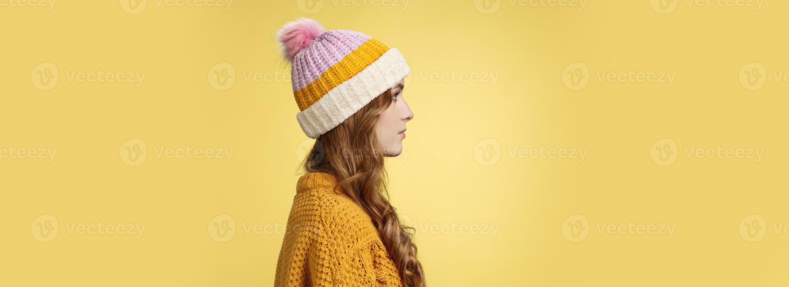 Profile shot attractive female curly hairstyle wearing hat knitted sweater standing queue order hot warm drink look left normal casual expression, posing yellow background studio photo