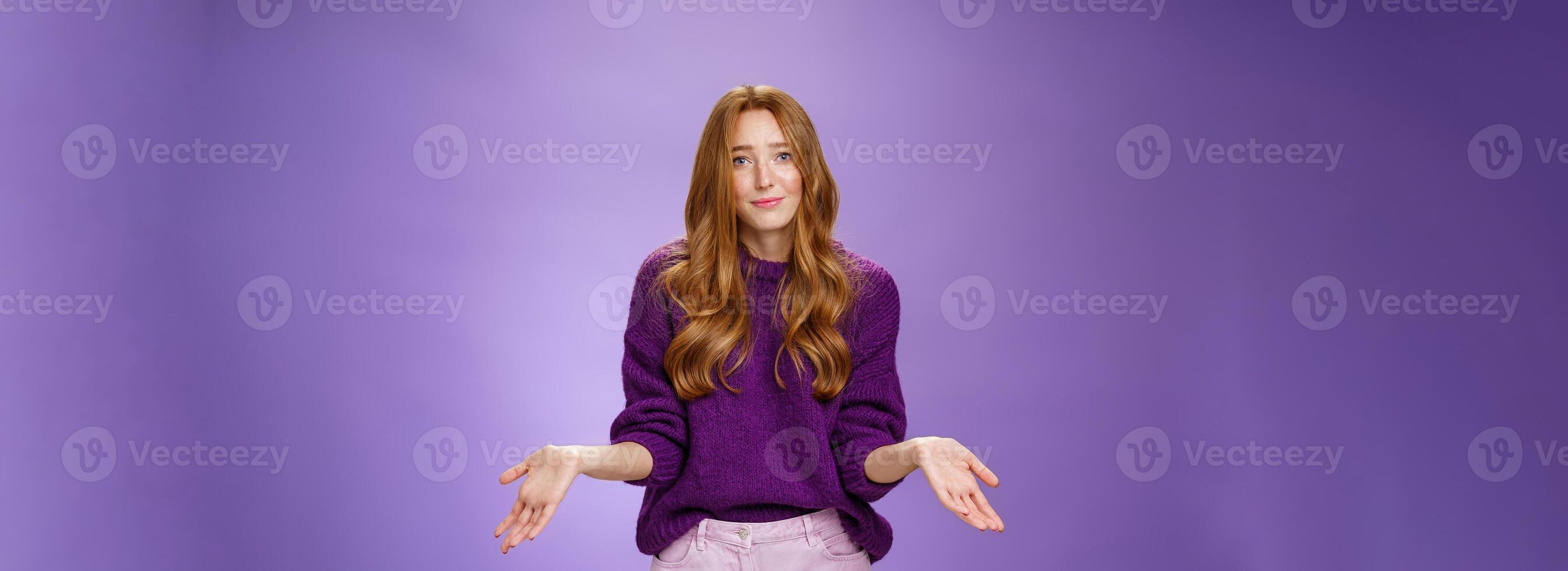 Who cares chill I not know. Portrait of clueless and unbothered cute redhead female in purple sweater smirking in sorry and shrugging with hands sideways being questioned and puzzled to answer photo