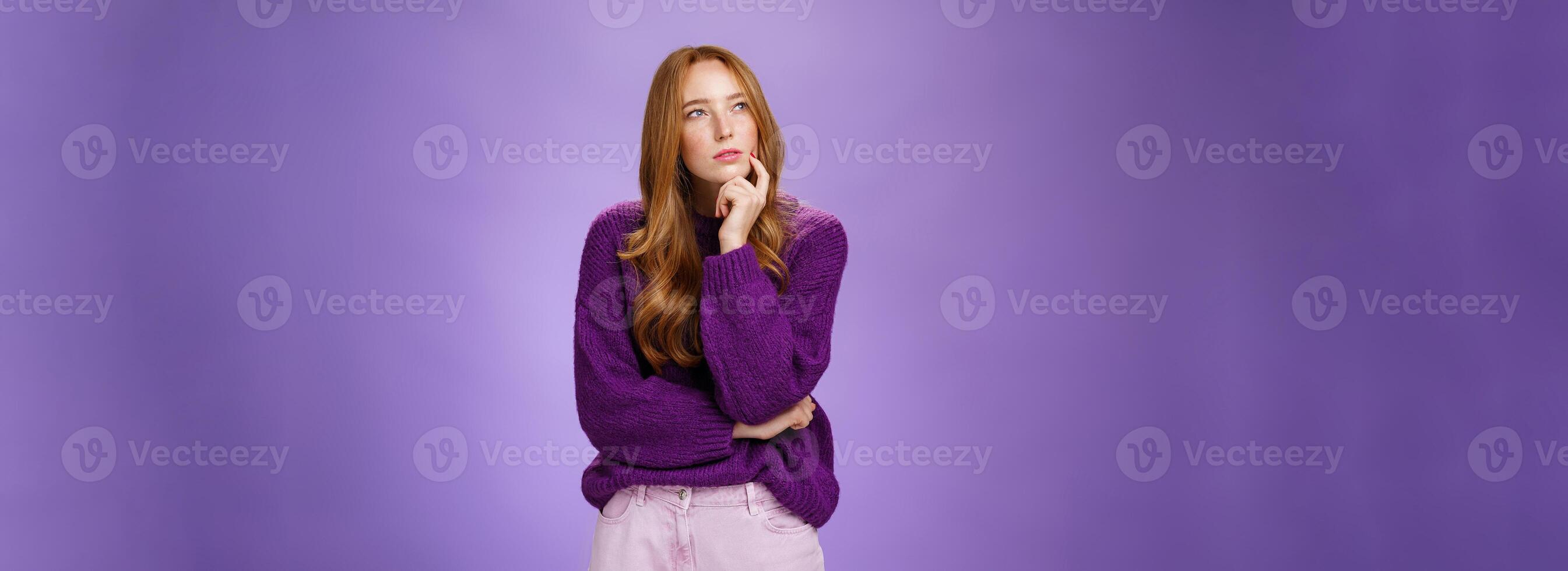Thoughtful and focused smart, creative attractive woman with red hair and freckles squinting, looking at upper left corner while thinking having idea or plan holding hand on chin as making up choice photo