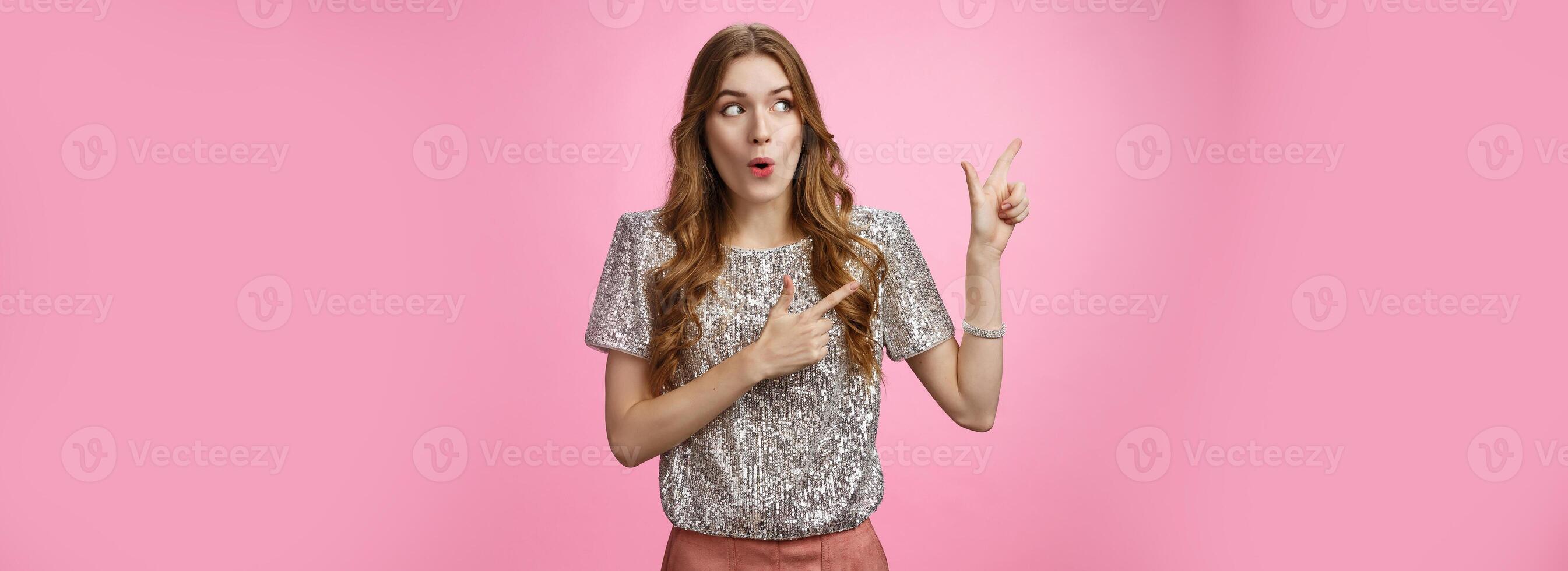Wow interesting. Portrait amazed intrigued attractive young 20s girl shopping curious see cool promo folding lips widen eyes thrilled looking pointing left sideways, standing pink background photo