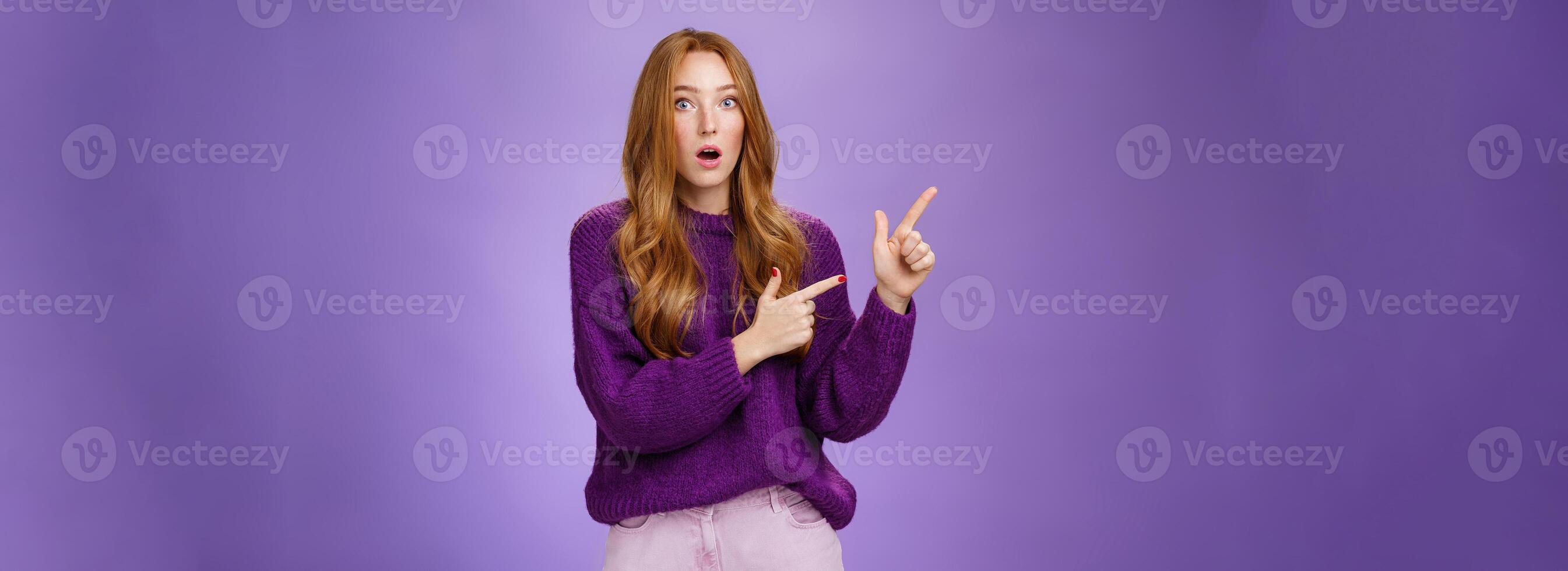 Stunned girl asking friend if she saw it drop jaw from stupor and amazement popping eyes at camera after witnessing shocking revelation pointing questioned at upper left corner over purple wall photo