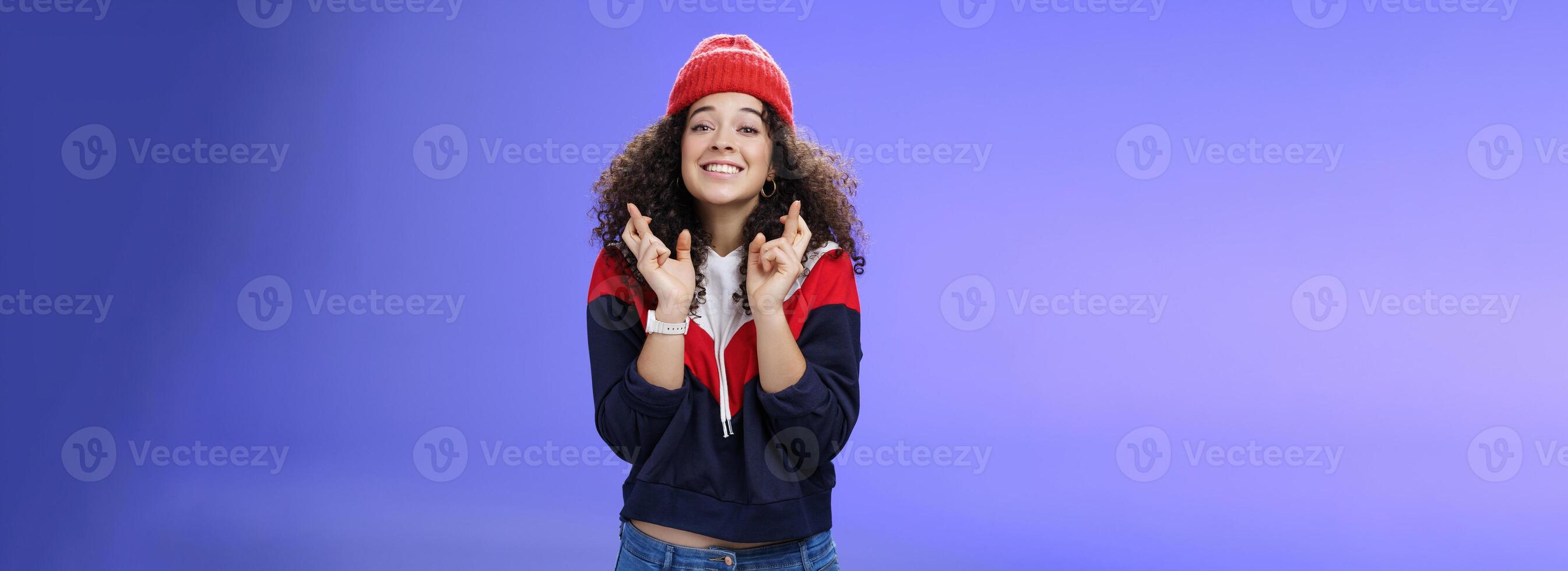 Dreamy optimistic woman praying friend will win standing supportive and excited smiling hopeful crossing fingers god good luck, waiting for miracle and dream come true posing against blue background photo