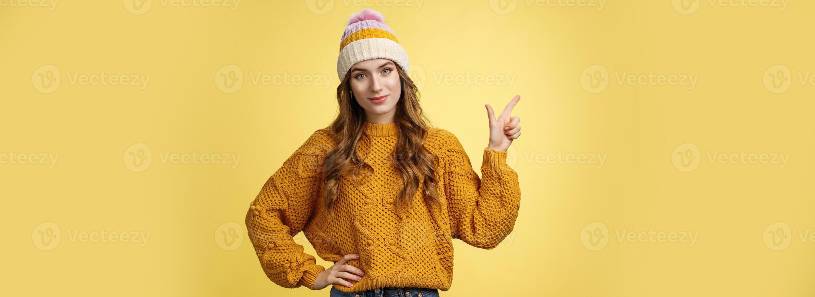 Confident good-looking young female friend telling you buy product immidietely pointing upper left corner smiling hold hand waist self-assured, employee help client pick best merch, yellow background photo