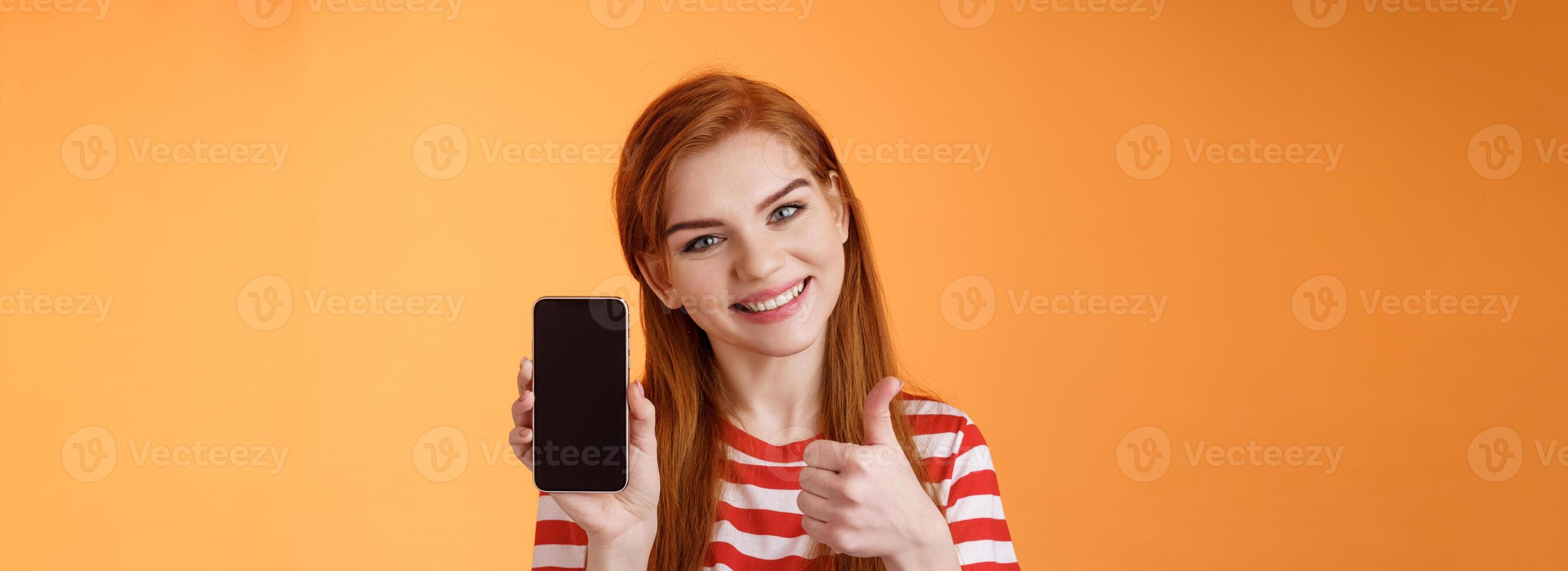 Best smartphone app guarantee. Assertive lovely friendly-looking redhead woman recommend cellphone application, introduce online store website, like give thumb-up approval, stand orange background photo