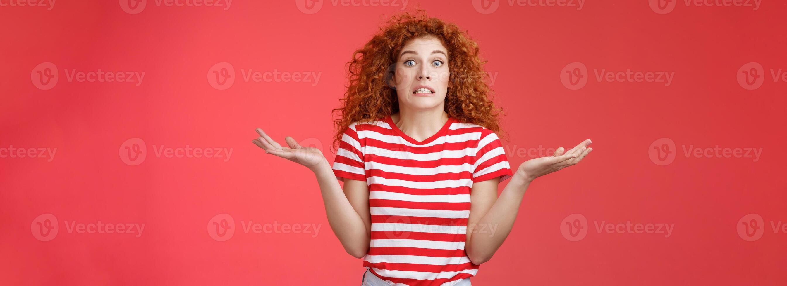 Yikes how should I know. Unaware worried awkward cute redhead curly girl clench teeth smirking uncertain panic cannot answer popping eyes confused shrugging hands spread sideways full disbelief photo