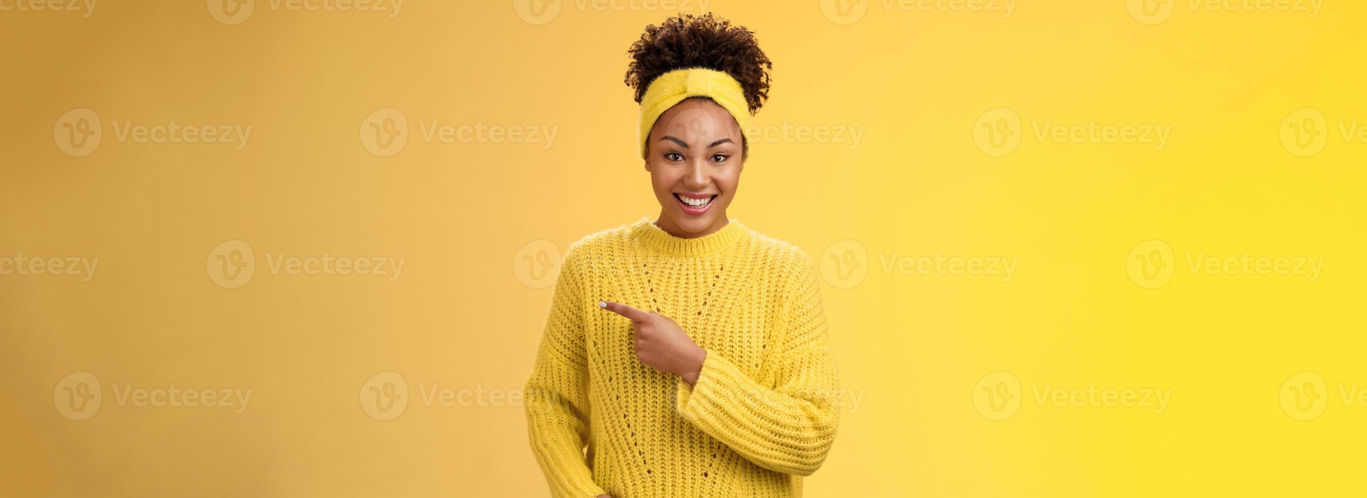 Friendly ougoing relaxed african-american woman casually pointing right during conversation discussing recent new cafe open awesome discounts promos standing happily yellow background photo