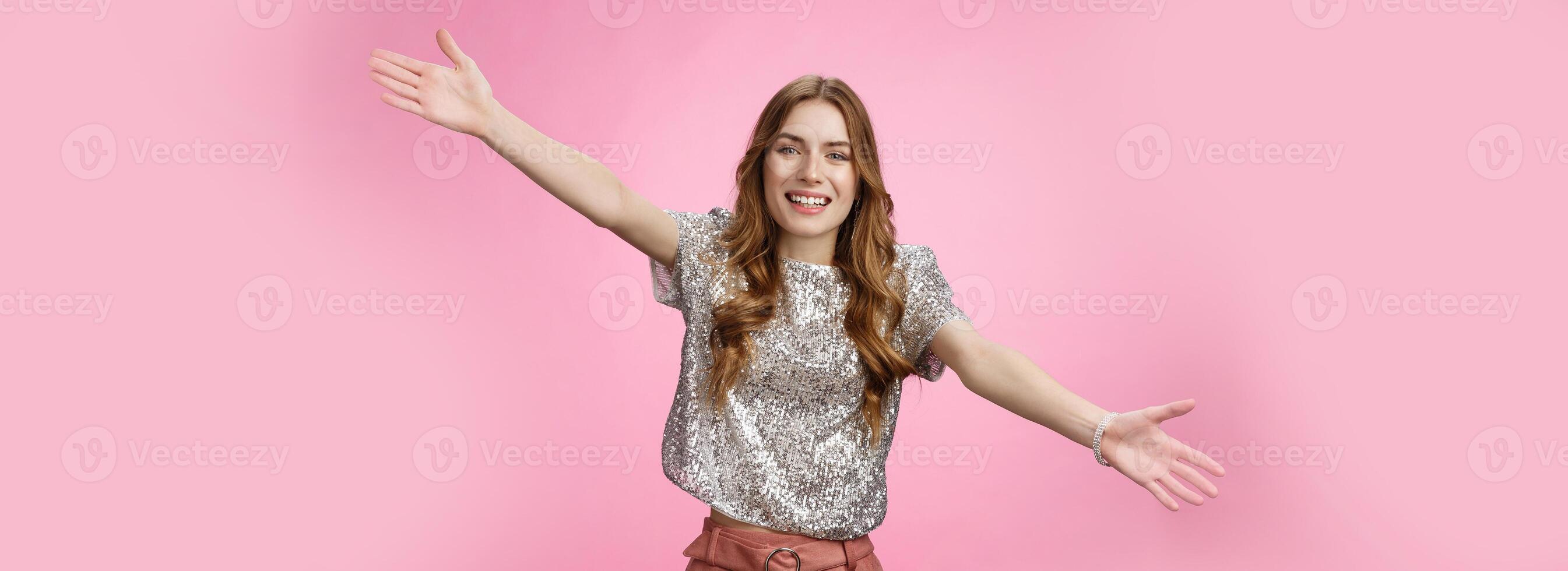 Come into my arms. Portrait friendly outgoing charming cute caucasian female wearing glittering blouse extend arms sideways wanna embrace cuddle friend welcoming hugging guests, smiling broadly photo