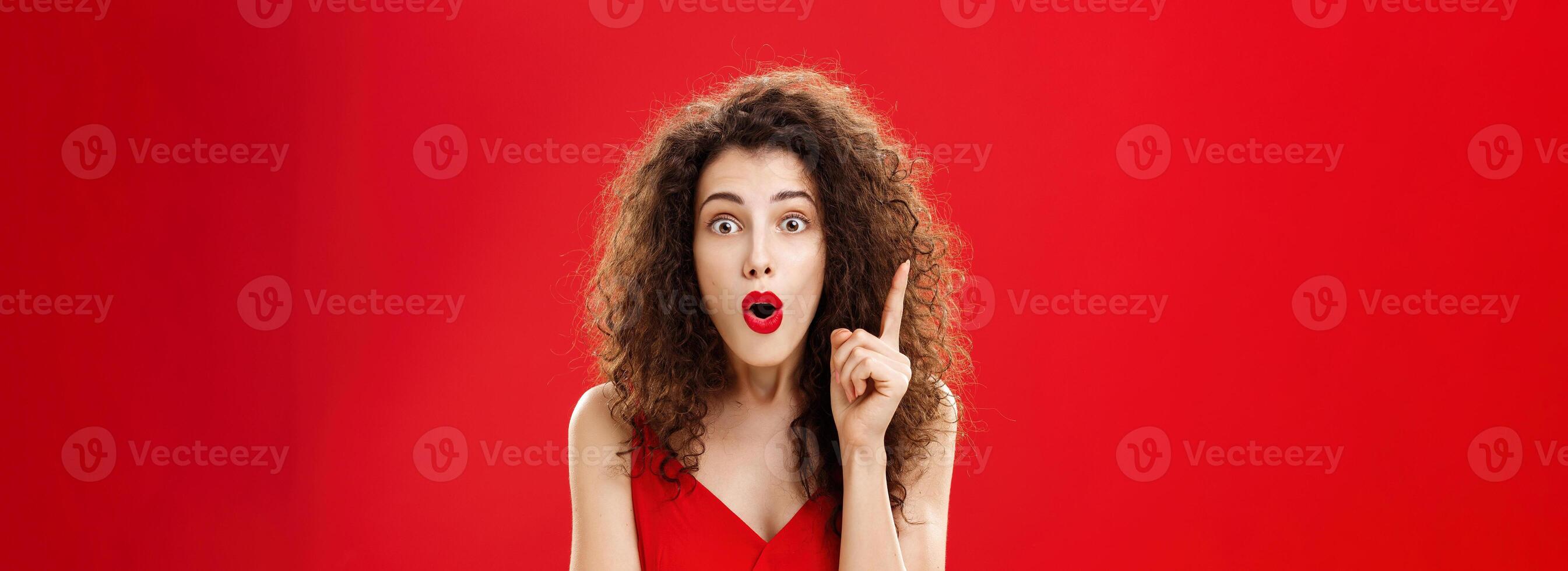 Woman remembered important information feeling excited adding suggestion with raised index finger in eureka gesture, folding lips in raising eyebrows being thrilled finally understanding photo
