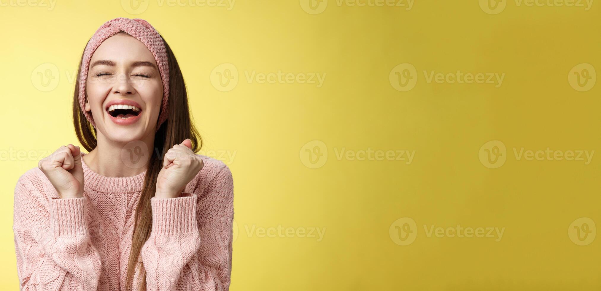 Relieved happy triumphing attractive european woman wearing pink knitted sweater yelling yes satisfied, raising fists in victory close eyes smiling, celebrating win, feeling lucky hearing good news photo