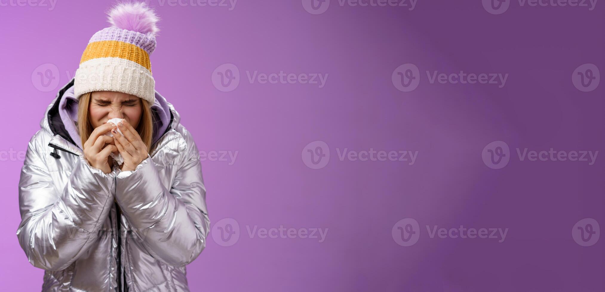 Girl runny nose sneeze tissue press napkin face got ill feeling unwell sick heading hospital standing purple background bending wearing silver stylish jacket winter hat, crying sobbing photo