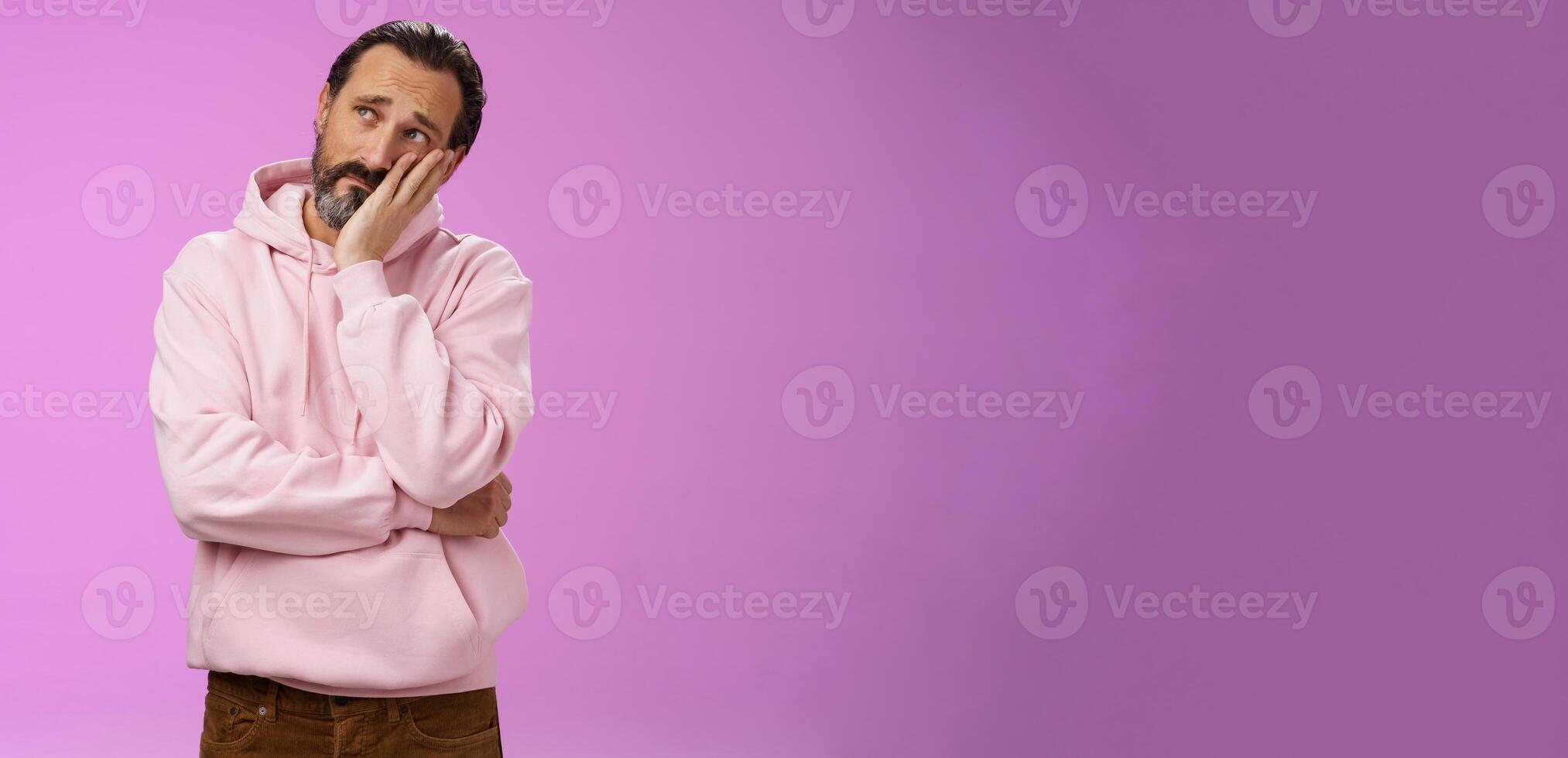 Sad gloomy bearded mature man lean head palm frowning look upper left corner thoughtful sorrow thinking bad times face hard problem standing upset disappointed down dumps, purple background photo