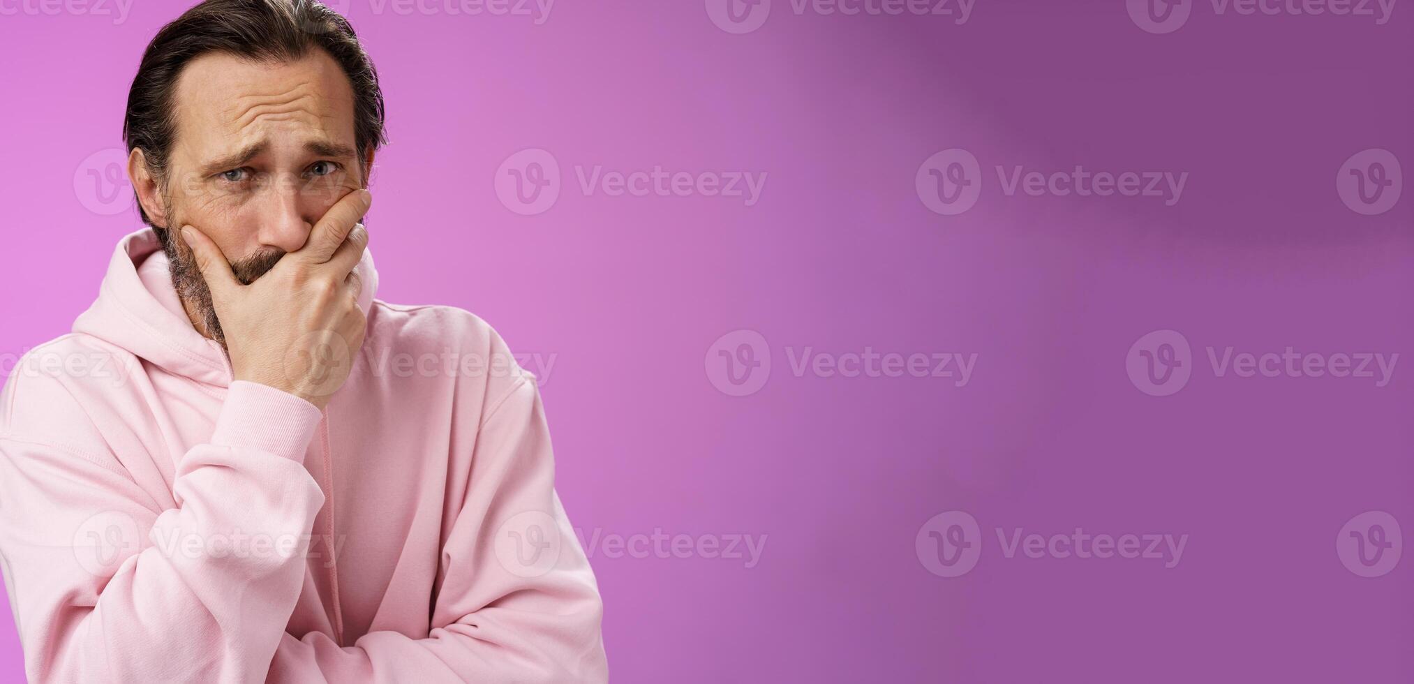 Shocked upset handsome mature bearded man hear terrible news griefing suffer sorrow express empathy gasping hold hand mouth reacting lose cringing crying cannot control emotions, purple background photo
