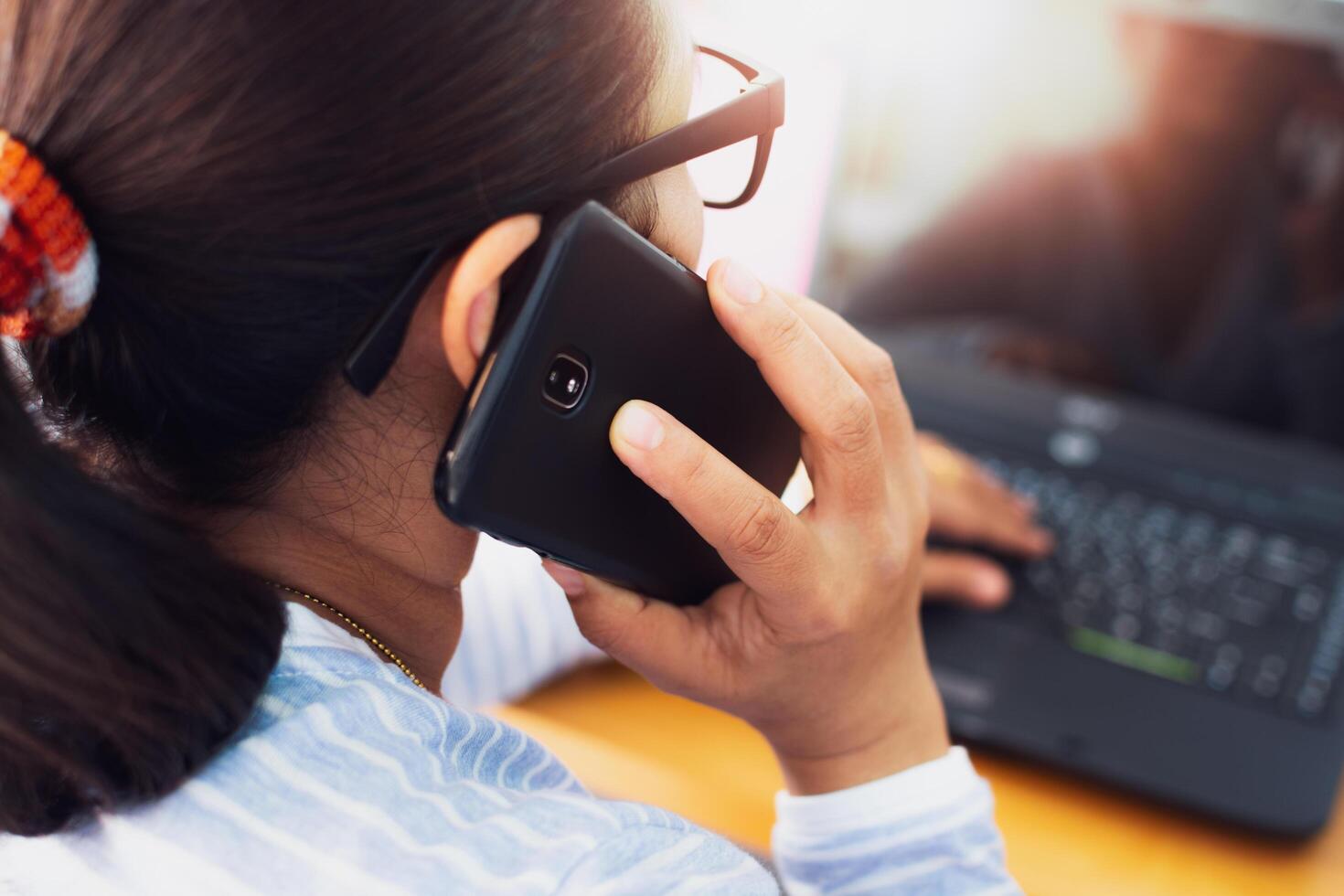 Woman talking on mobile phone and working on laptop. photo