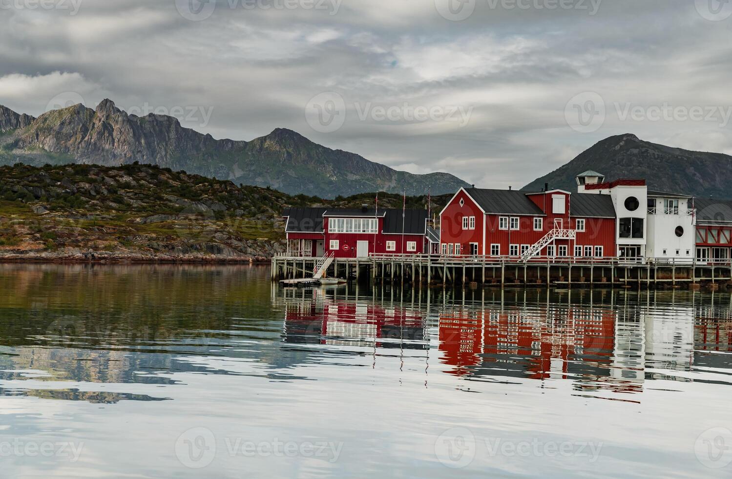 a classical building for stopping yacht travellers, fishing house of red color on the coast on Lofoten Islands, classic norwegian landscape, rocky coast with dramatic sky photo