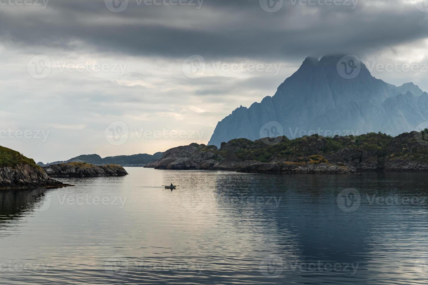 a man paddles on a small boat among the rocks, norwegian classical seascape, rocky coast with dramatic skies, the sun breaks through the clouds, sheer cliffs, small islands illuminated by the sun photo