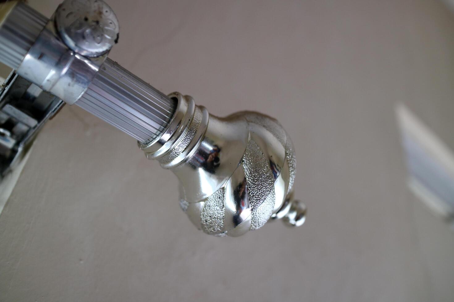 The curtain pole end cap with a round tapered shape with a chrome color, made of plastic photo