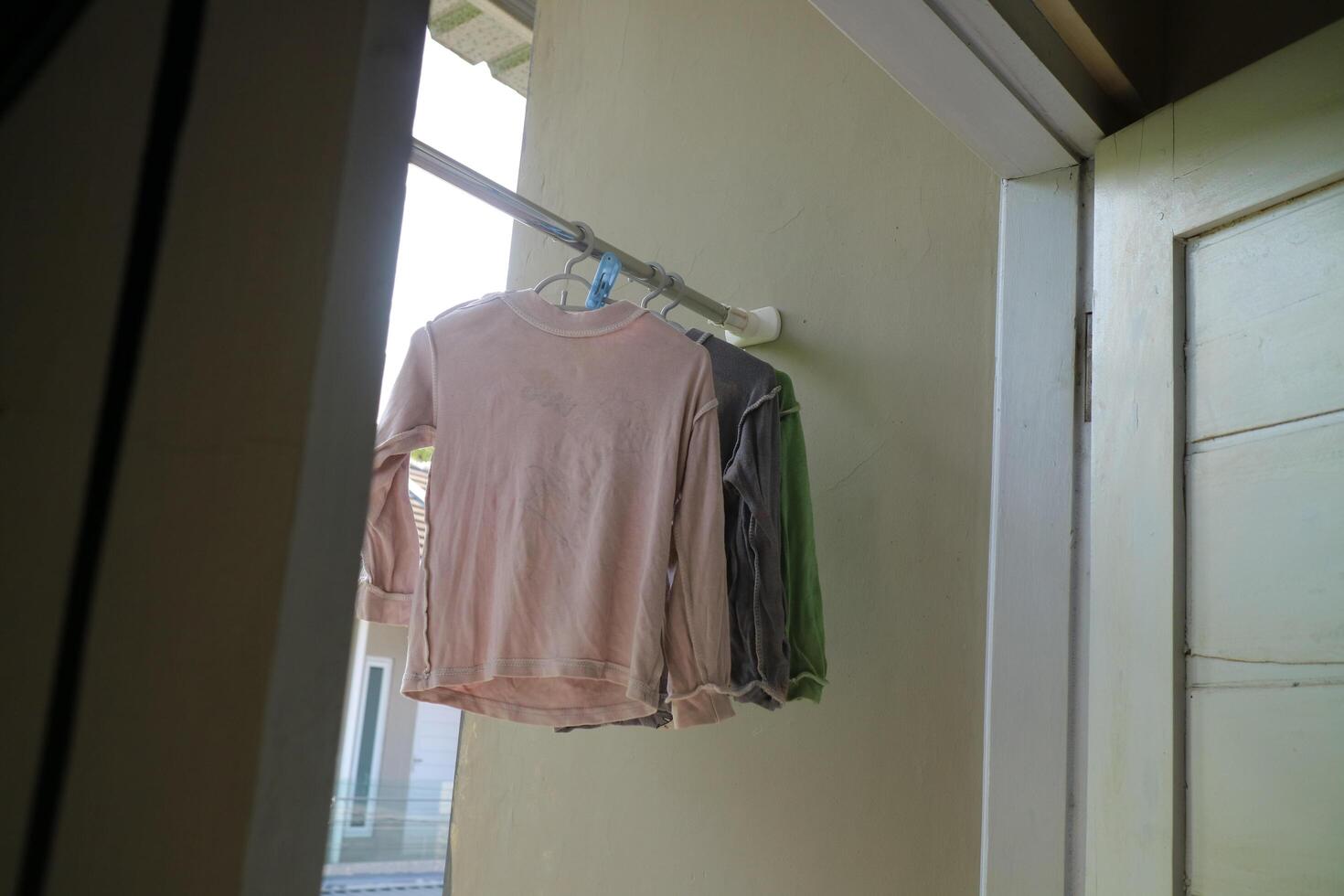 Several long sleeve children's t-shirts are drying on the balcony of the house during the day photo