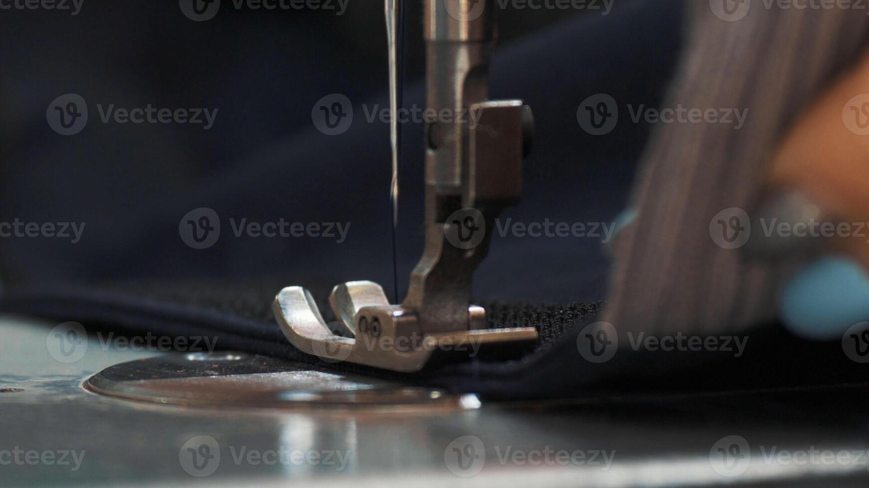 Hands of seamstress sewing with a professional machine embroiders sews on red fabric using both sides of the material Concept of Factory Home At Work Professionals. photo