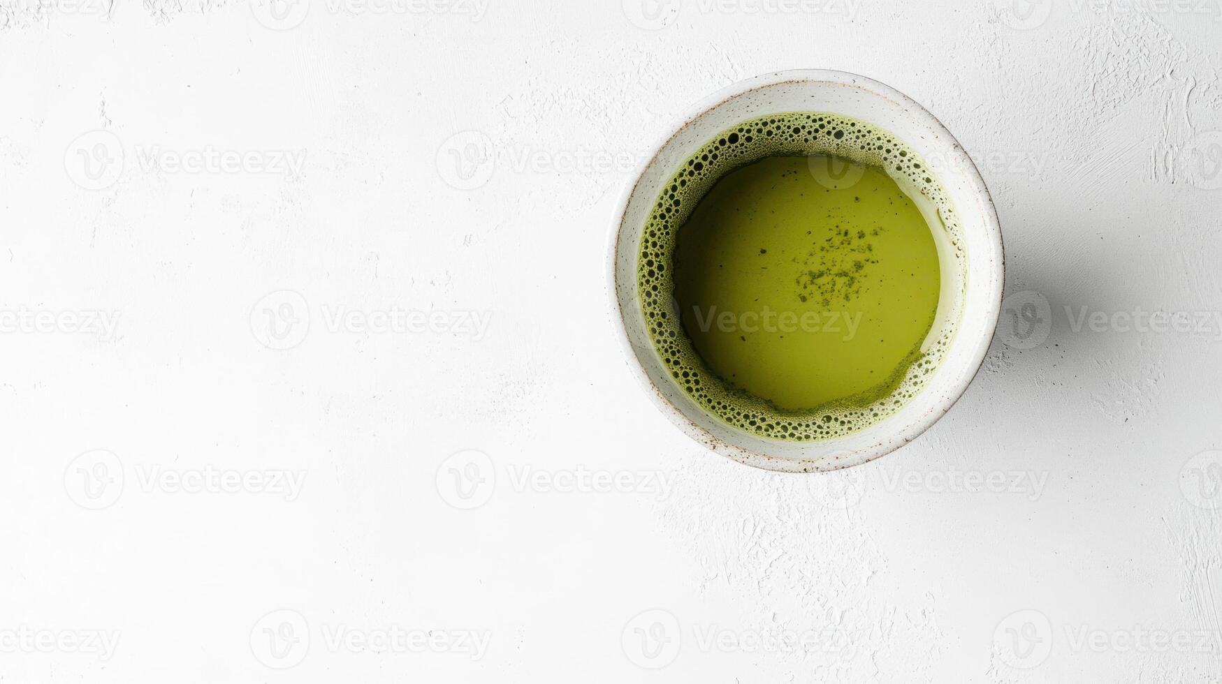 Overhead view of a cup of matcha green tea on a white surface. photo