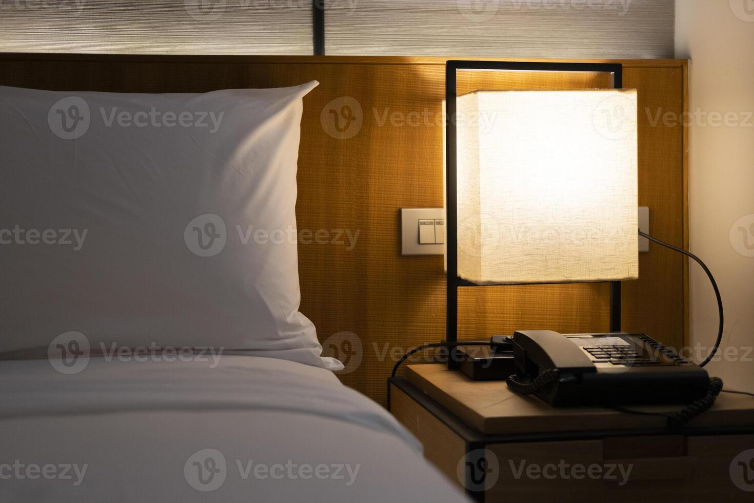 Modern Japanese style bedroom headboard with bed and pillows for sleeping and resting in a dim atmosphere with a bedside light on. Accommodation, hotel. photo