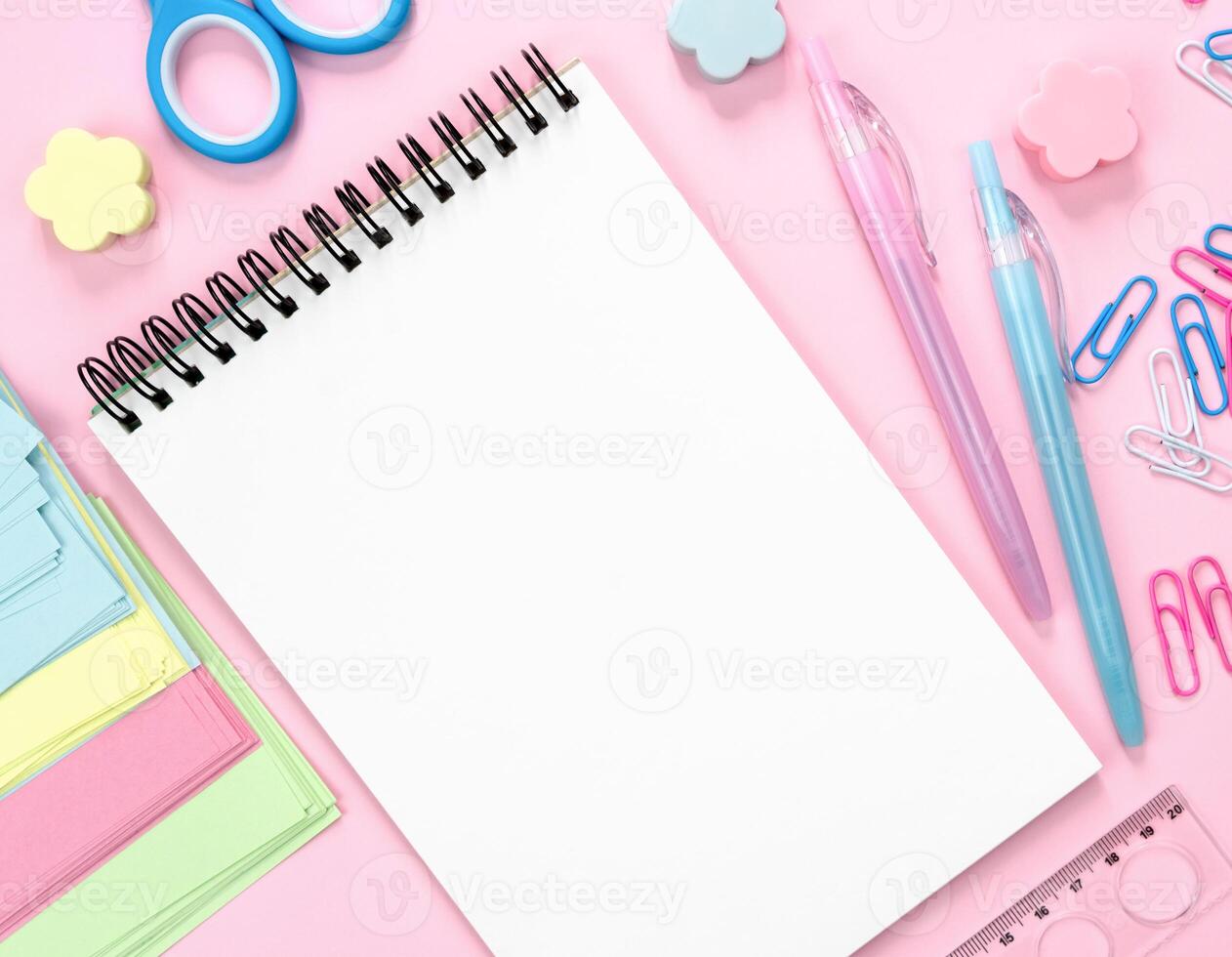 Flatlay composition with blank notepad and school stationery on a pink background. Back to school. Top view. Copy space. photo