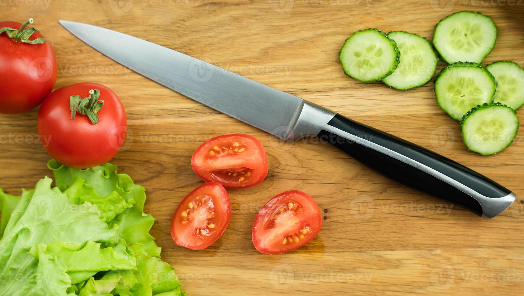 Fresh tomatoes and cucumbers for salad on a wooden board. Preparation of vegetable dietary salad. Close-up. Selective focus. photo