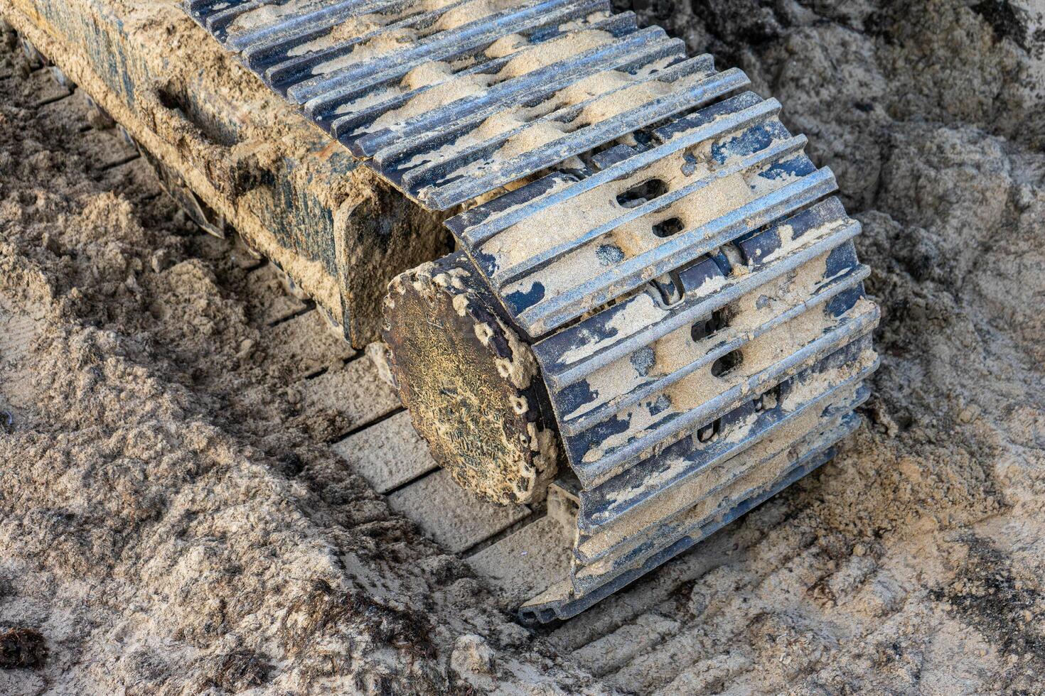 Close-up of excavator caterpillars on rough terrain, showcasing detailed treads and dirt accumulation. Ideal for construction and machinery themes. photo