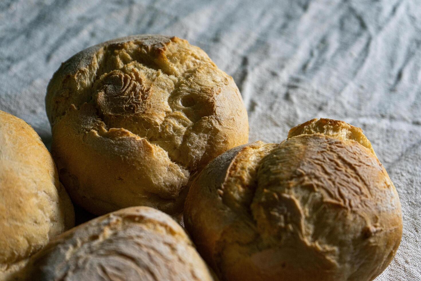 A closeup of traditional Alentejan bread rolls, known as papo-secos, freshly baked with a golden crust, displayed on a rustic wooden surface, showcasing their texture and artisanal quality. photo
